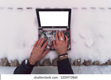 work on a small laptop covered with snow outside on a cold winter day after a snowfall