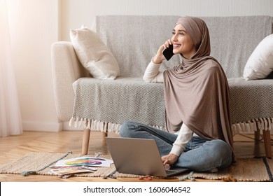 Work Opportunities For Muslim Women Concept. Smiling Arabic Girl In Hijab Talking On Cellphone And Using Laptop While Sitting On Floor At Home. - Powered by Shutterstock