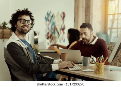 Work is pleasure. Smiling Caucasian businessman in glasses feeling good in the office while working with his team. - Shutterstock ID 1317233270