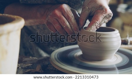 Work in pottery workshop: clay ware on throwing wheel, master ceramist molding clay using professional tools. Creating ceramic utensils and traditional occupation concept.