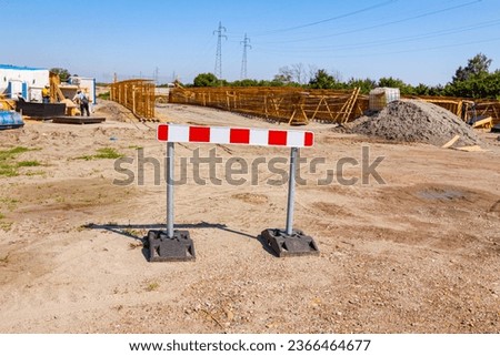 Work in progress, boundary sign, red and white stripes on it, barrier with stabilizer set on the building site. 