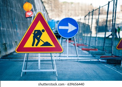 Arbeiten in Arbeit. Straßen, Straßenschilder. Männer auf der Arbeit. Einige Zeichen signalisieren Arbeit in der städtischen Straße. Hindernisse und Straßenschilder. Silhouette eines Arbeitnehmers bei der Arbeit. Rechter Pfeil.