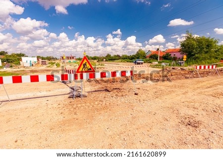 Work in progress, triangle sign with boundary, caution symbol, trench is on construction site. 