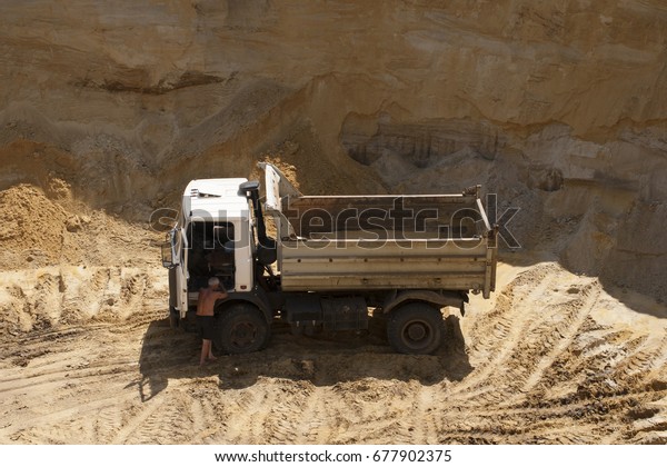 Work\
in the quarry. The truck on the loading of the\
sand.