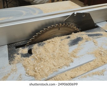 At work sawing wood. Circular saw. A table saw machine which saws wood, particle Board and fiberboard. Sawdust. Industrial production of furniture. - Powered by Shutterstock