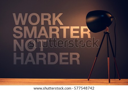 Work smarter not harder, motivational quote on office wall illuminated with desk lamp