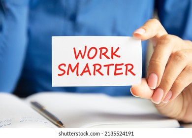 work smarter is written on a white business card in a woman's hand. Blue background. Business and advertising concept