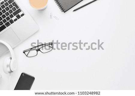 Work space concept. Top view of laptop, white headphones, black cell phone, notebook, glasses and coffee on white background with copy space. Flat lay