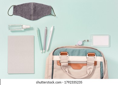 Work Space New Normal Concept. School Bag And School Accessories, Face Medical Mask And Hand Sanitizer On Mint Colored Paper Background.  Close Up, Top View.