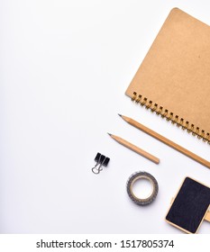 Work space with notebook,pencil and black bpard over white background