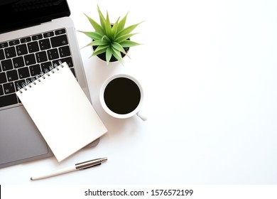 Work space office business and finance concept on modern table desk with blank notepad and laptop computer, coffee cup and green plant, Top view with copy space, flat lay - Powered by Shutterstock