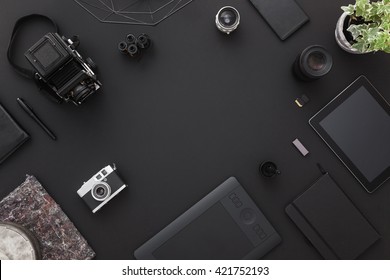 Work Space On Black Table Of A Creative Designer Or Photographer With Laptop, Tablet, Cameras Other Objects Of Inspiration And Copy Space. Stylish Home Studio Concept Of Technology Trends.