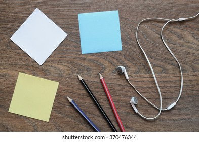 Work space table with paper, pencil, and headphone on wood background