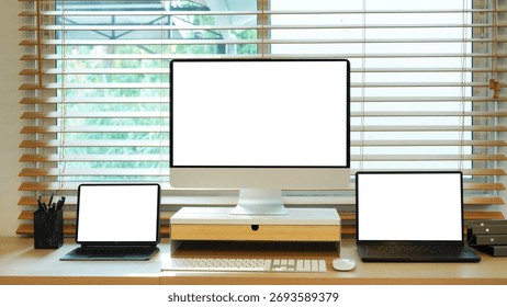 work station setup featuring a modern desktop computer along side a portable laptop computer and tablet arranged neatly on a wooden desk surface for maximum productivity.