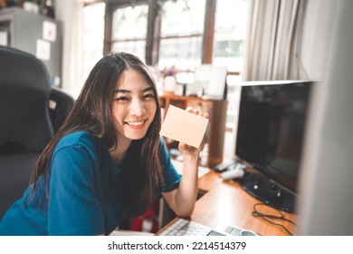 Work And Study Online From Home WFH Office Concept. Portrait Of Young Asian Cute Student Teenager Woman Hold A Note Paper For Remind. Eye Looking At Camera