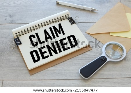 work table is light. envelope and magnifier. text on notepad page. Claim Denied