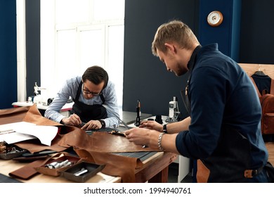 The work of tailors in the workshop, 2 young craftsmen in the workshop for sewing leather bags during work, handmade leather goods, family small business