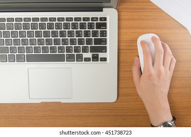 Work Time.Businessman's Hand Clicking Mouse With Laptop On Wooden Table.Top View.