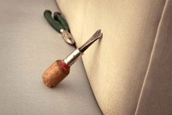 Work Tools Of An Upholsterer. Staple Remover Resting On A Sofa.