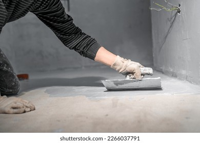 work with trowel on floor and wall in new room in building