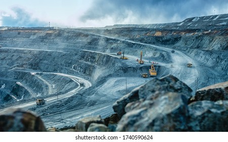 Work of trucks and the excavator in an open pit on gold mining, soft focus