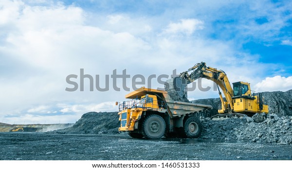 Work of trucks and the excavator in an open pit on
gold mining, soft focus