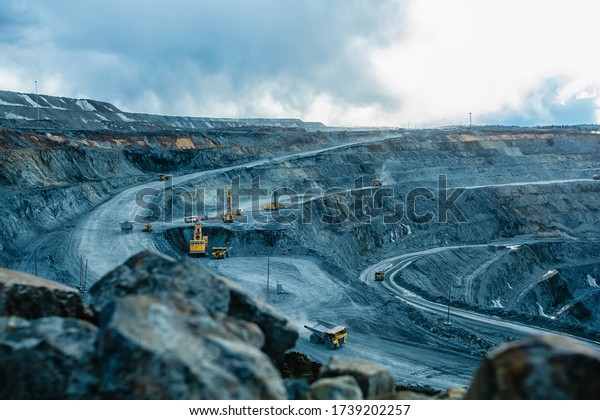 Work of trucks and the excavator in an open pit on\
gold mining
