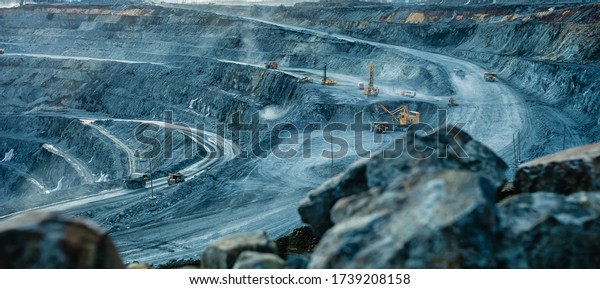 Work of trucks and the excavator in an open pit on\
gold mining, soft focus