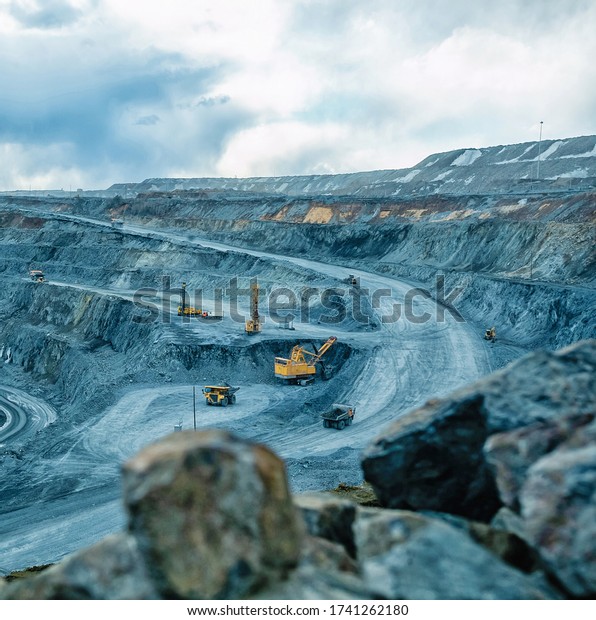 Work of trucks and the excavator in an open pit on\
gold mining, soft focus