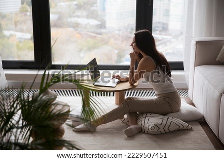 work from vacation home, remote workers. Working from Anywhere.  woman freelancer connecting to the Internet from home. The adorable  young woman using a laptop, in a stylish living room. 