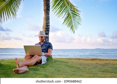 Work And Vacation. Young Man Working On Laptop Computer On The Tropical Beach Under The Palm Tree.