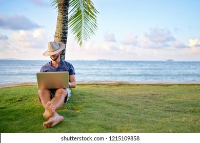 Work And Vacation. Young Man Working On Laptop Computer On The Tropical Beach Under The Palm Tree.