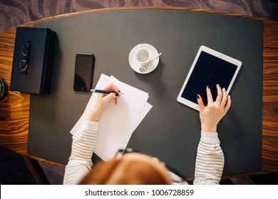 work woman writing on paper with digital tablet computer in office room. top view