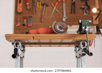 Workbench featuring a grinder and a vice with numerous tools neatly organized on the wall, depicting a work or hobby space