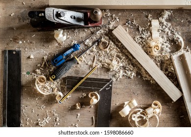 Workbench with a variety of hand tools in a woodworking or cabinetmaking workshop including chisels, screwdrivers, tape measure, pencil, ruler
