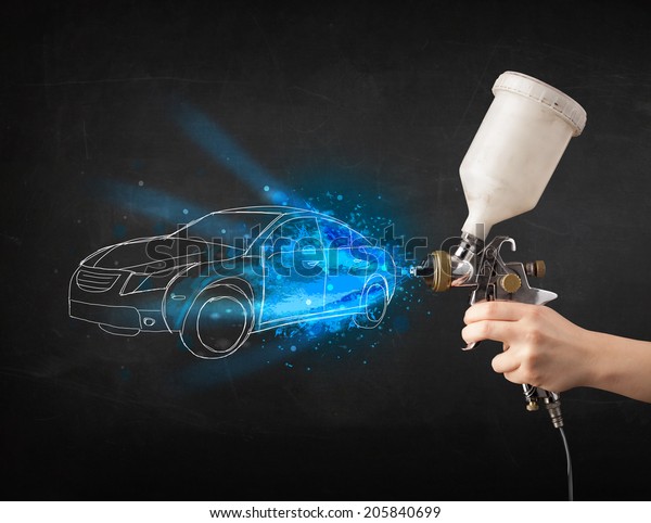 Worker with airbrush gun painting hand drawn white\
car lines