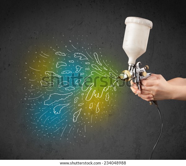 Worker with airbrush gun paints colorful lines\
and splashes concept