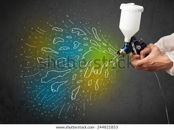 Worker with airbrush gun paints colorful lines\
and splashes concept