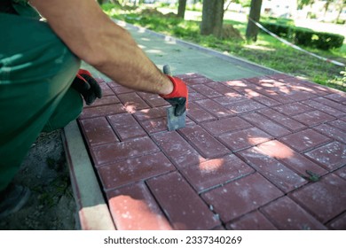 A worker aligns the gaps between the individual paving blocks.