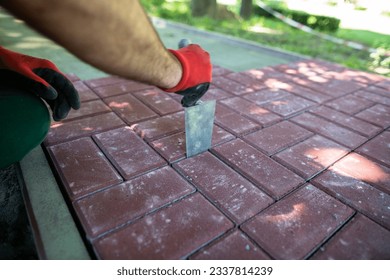 A worker aligns the gaps between the individual paving blocks.