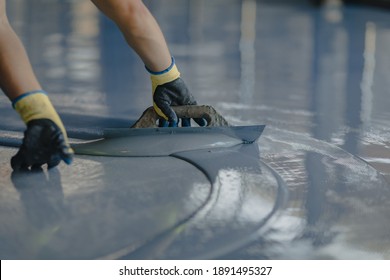 The Worker Applies Gray Epoxy Resin To The New Floor