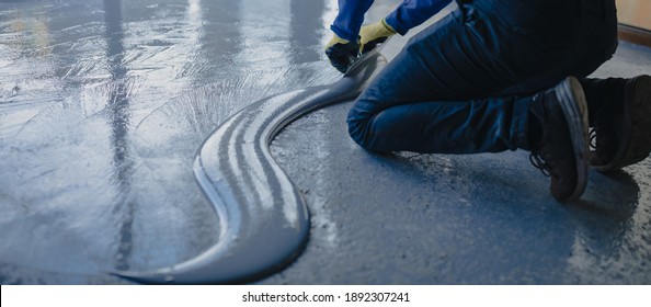 The Worker Applies Gray Epoxy Resin To The New Floor