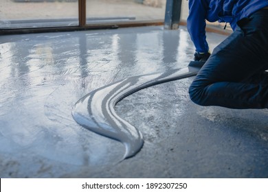 The Worker Applies Gray Epoxy Resin To The New Floor