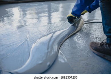 The Worker Applies Gray Epoxy Resin To The New Floor