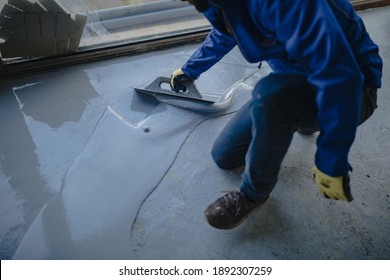 The Worker Applies Gray Epoxy Resin To The New Floor