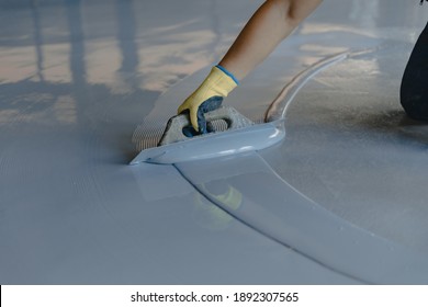 The worker applies gray epoxy resin to the new floor - Powered by Shutterstock