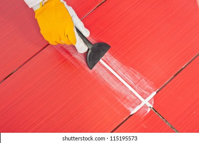 Worker Applies  Grout Whit Rubber Trowel Red Tiles