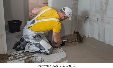 A worker applies a liquid membrane on the bathroom floor. Foolproof waterproofing under a tile bathroom.