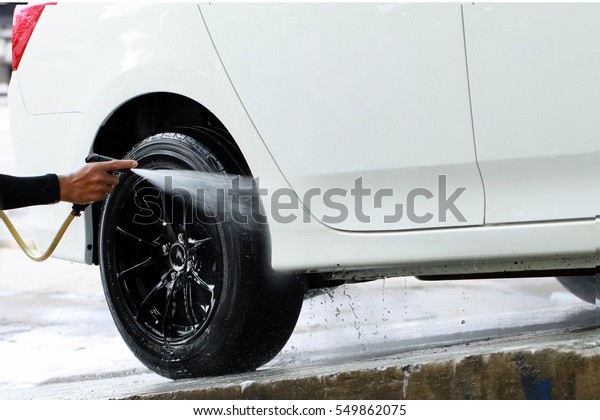 A worker apply\
water jet to a Car for his car care business ,  washing car by high\
pressure water jet