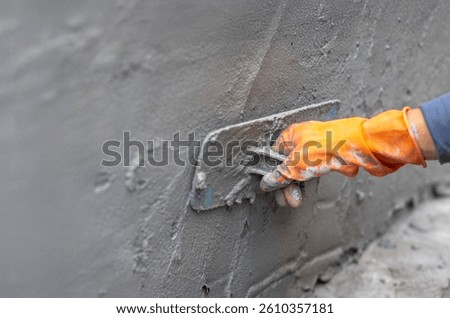Worker applying cement on wall in construction site.